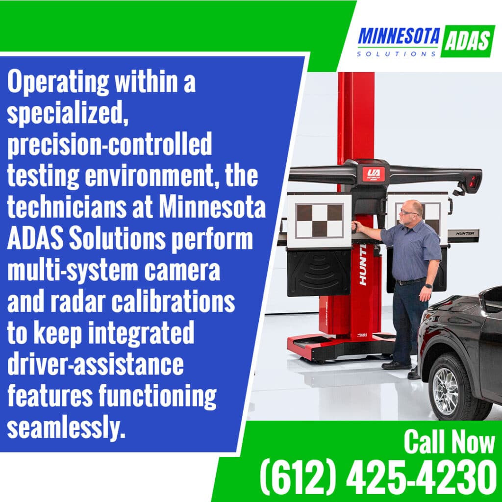 A technician operating a red Hunter Ultimate ADAS calibration fixture with target boards next to a black vehicle inside a precision testing facility.