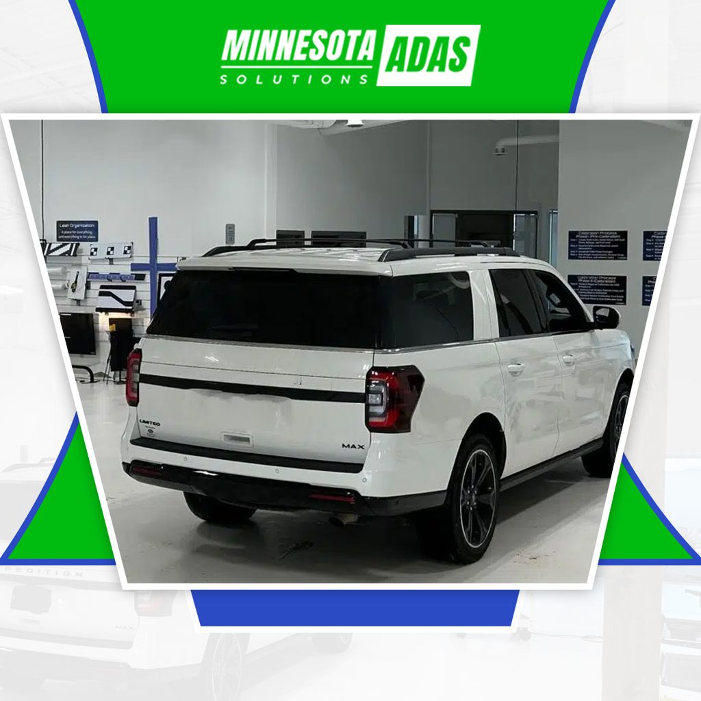 Rear three-quarter view of a white SUV parked inside a specialized ADAS calibration bay with alignment targets mounted on the wall.